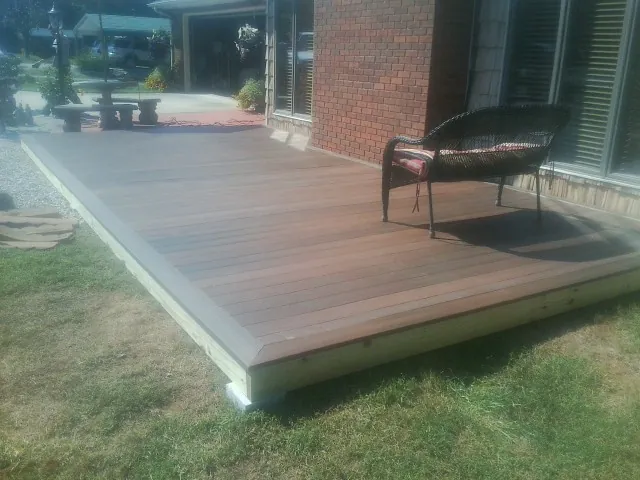 New wood deck and wicker chair beside a brick house in Liberty