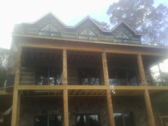 Dormers and porch framing on a large log home under construction — Roof Coating work by our crew in Liberty